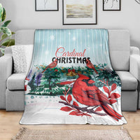 Cardinal Christmas blanket draped on sofa, featuring red birds and evergreen holiday greenery.