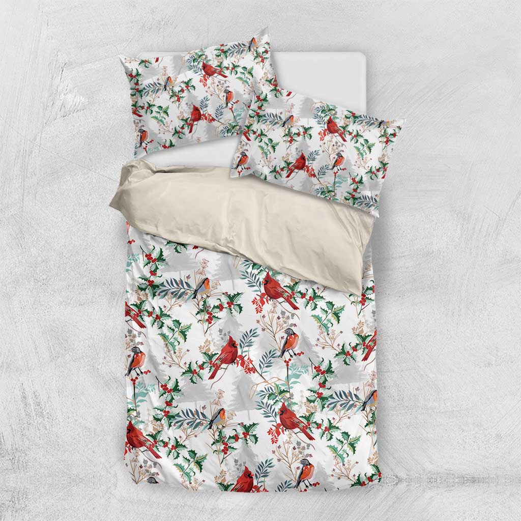 White bedding set laid flat: duvet and pillowcases with red cardinal and green foliage