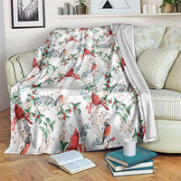 Christmas blanket in white with red cardinal birds and green leaf pattern, draped on sofa