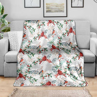 Christmas blanket with red cardinals and green leaves on a white background, on gray couch