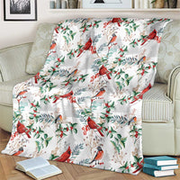 Christmas blanket with cardinal bird pattern, white base with red and green accents on couch