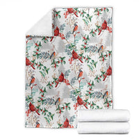 Christmas blanket with cardinal bird pattern, white with red and green leaves, folded stack