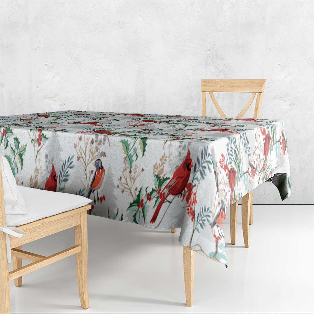 White Christmas tablecloth with red cardinals and green foliage pattern, hanging over table