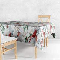 White Christmas tablecloth with red cardinals and green foliage pattern, hanging over table
