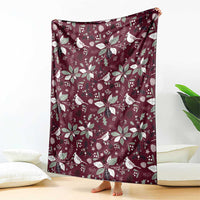 Wine red blanket with repeating white bird and poinsettia pattern, draped on floor.
