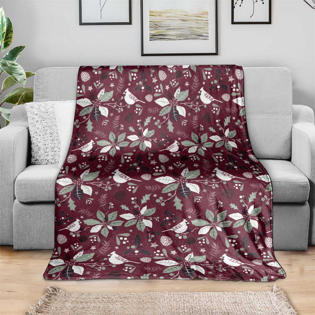 Wine red Christmas blanket with white birds and poinsettia flowers, spread over sofa.