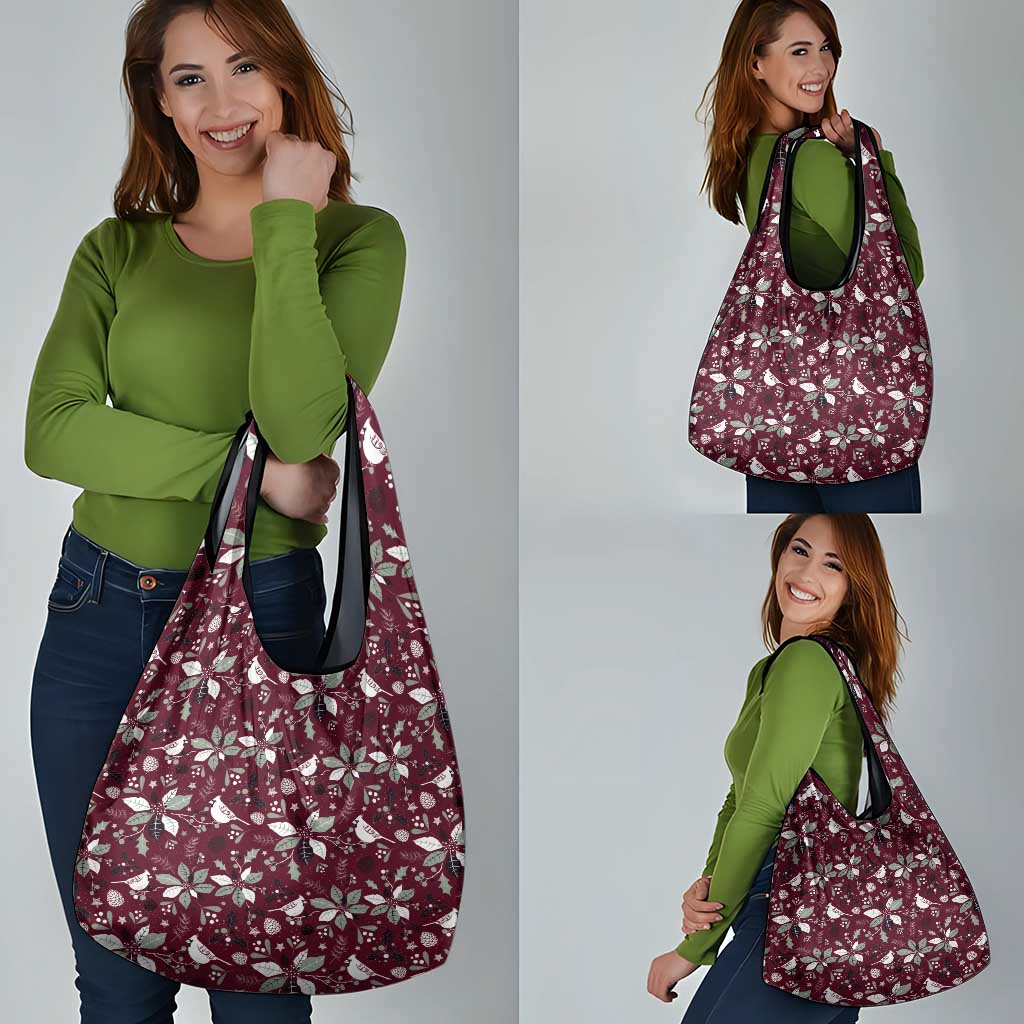 Wine red holiday tote bag with white botanical pattern shown being carried with dual handles