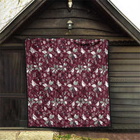 Wine red Christmas quilt with white poinsettia and bird pattern, hanging on a wall