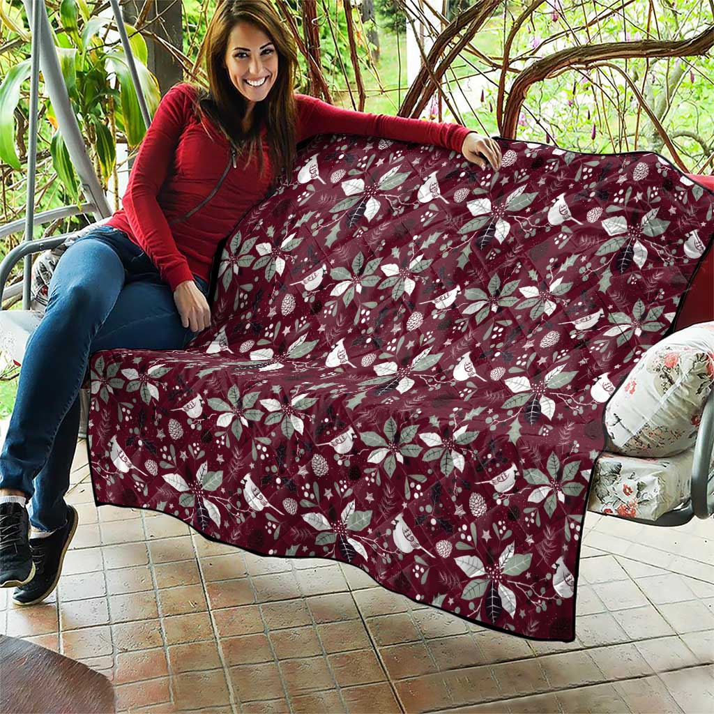 Wine red Christmas quilt with white poinsettia and bird motifs, spread on patio