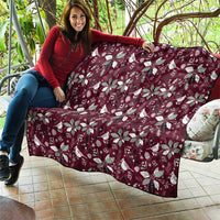 Wine red Christmas quilt with white poinsettia and bird motifs, spread on patio