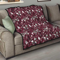 Wine red Christmas quilt with white poinsettia and bird pattern, draped over sofa
