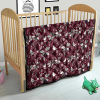 Wine red Christmas quilt with white poinsettia and bird motifs, on a crib mattress