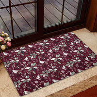 Wine red rubber doormat with festive bird and poinsettia pattern near door