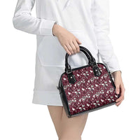 Wine red floral handbag with black handles, held for carrying