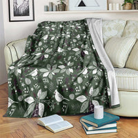 Green Christmas throw blanket with white bird, leaf, and star pattern