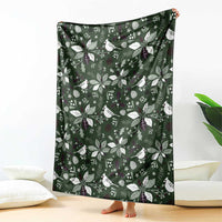 Green patterned blanket draped upright with white birds, leaves, and small stars