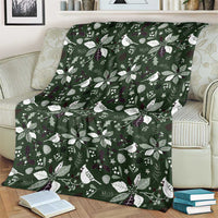 Green Christmas throw blanket with white birds and botanical pattern, laid flat