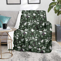Green Christmas blanket with white bird, leaf, and star motifs, draped over a seat