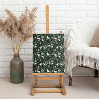 Green canvas wall art on easel with bird and foliage Christmas pattern.