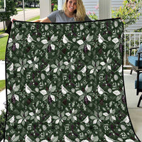 Green Christmas quilt with repeating white bow and leaf motifs, stitched border