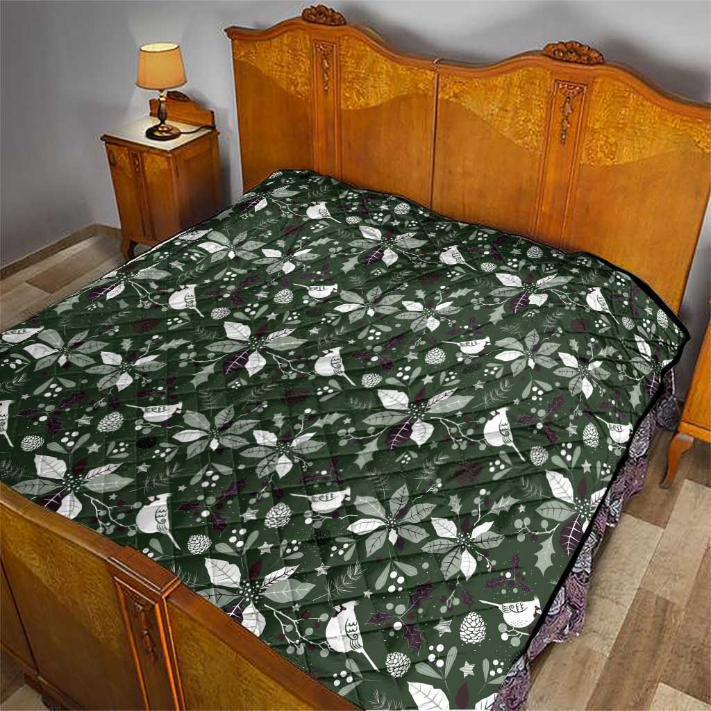 Green Christmas quilt with white bow-and-leaf pattern over bed, stitched edges