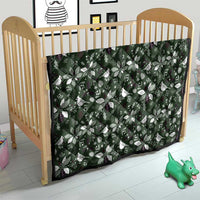Green Christmas quilt with white Christmas motifs, stretched over a wooden crib