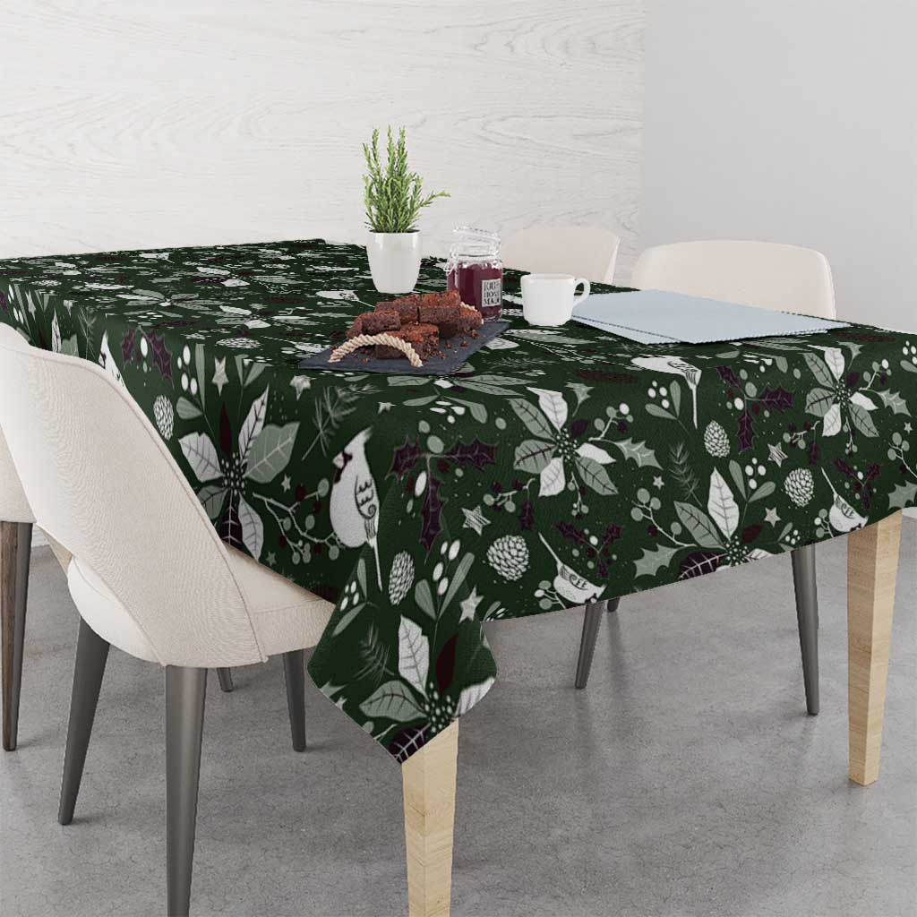 Green Christmas tablecloth with white bird, leaf, and pinecone motifs across table.