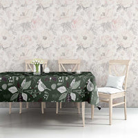 Green Christmas tablecloth with white birds and foliage pattern on long dining table.