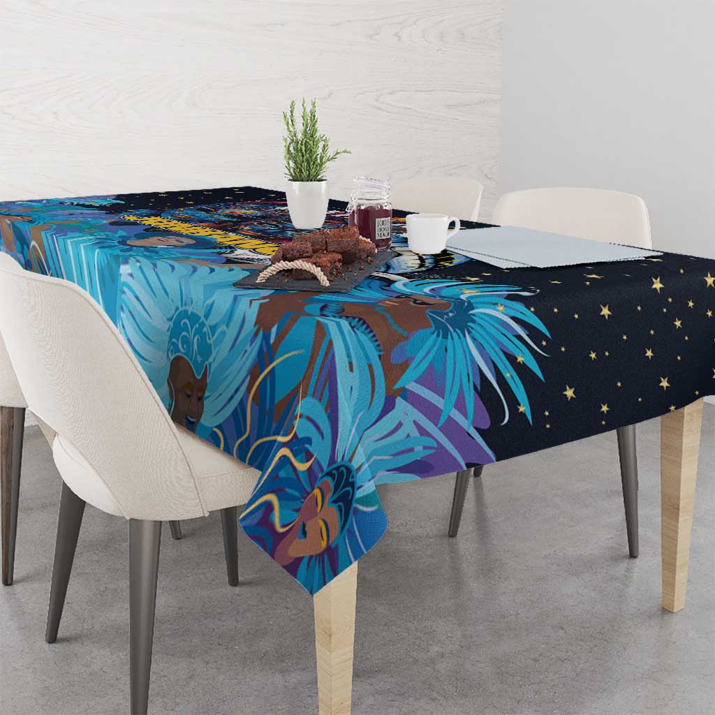 Blue tablecloth draped on table with Junkanoo mask print and palm motif