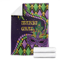 Mardi Gras decorative blanket, purple green mask and fleur-de-lis pattern with folded white rolls