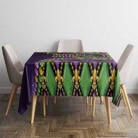 Mardi Gras tablecloth on square table, purple green and gold fleur-de-lis mask motif
