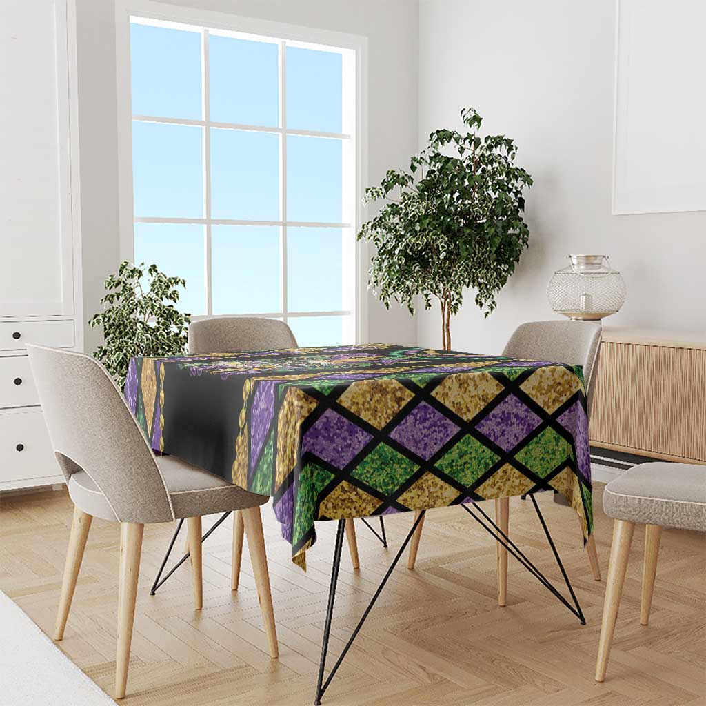 Multicolor diamond-pattern Mardi Gras tablecloth draped over dining table with purple and green