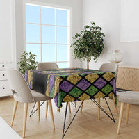 Multicolor diamond-pattern Mardi Gras tablecloth draped over dining table with purple and green