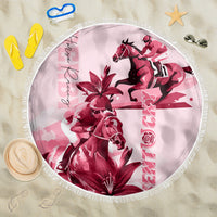 Pink round beach blanket with fringe edge, horse and lily graphic, vertical text.