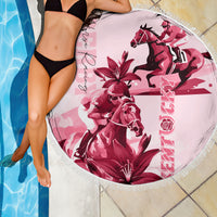Pink round beach blanket with fringe edge, horse and lily artwork, resting by pool.
