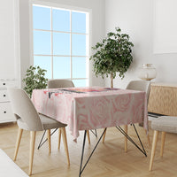 Pink rose-pattern tablecloth on dining table with chairs near the window