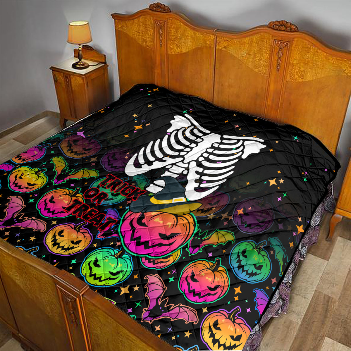 Black Halloween skeleton quilt laid on bed with colorful pumpkin and 'Trick or Treat' art