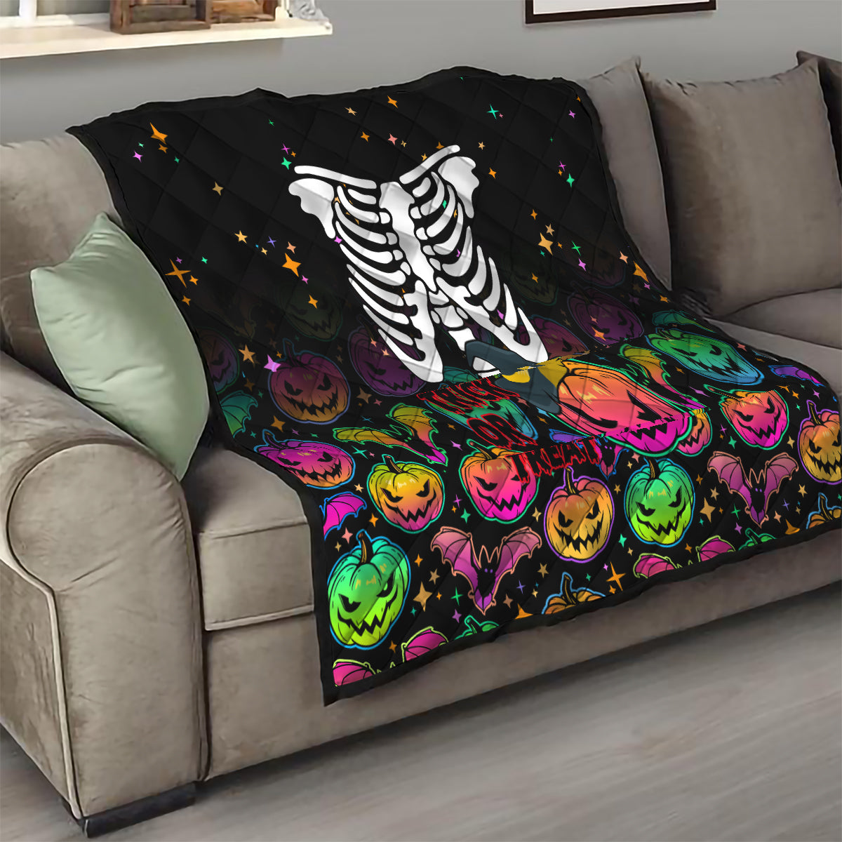 Black Halloween skeleton quilt draped on sofa with colorful pumpkins and star accents