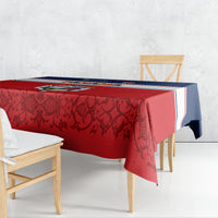 Tablecloth draped on dining table, red base with dark vine pattern and blue trim