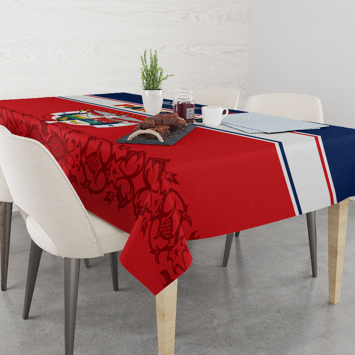 Red tablecloth with dark floral/vine pattern and blue-white border on dining table