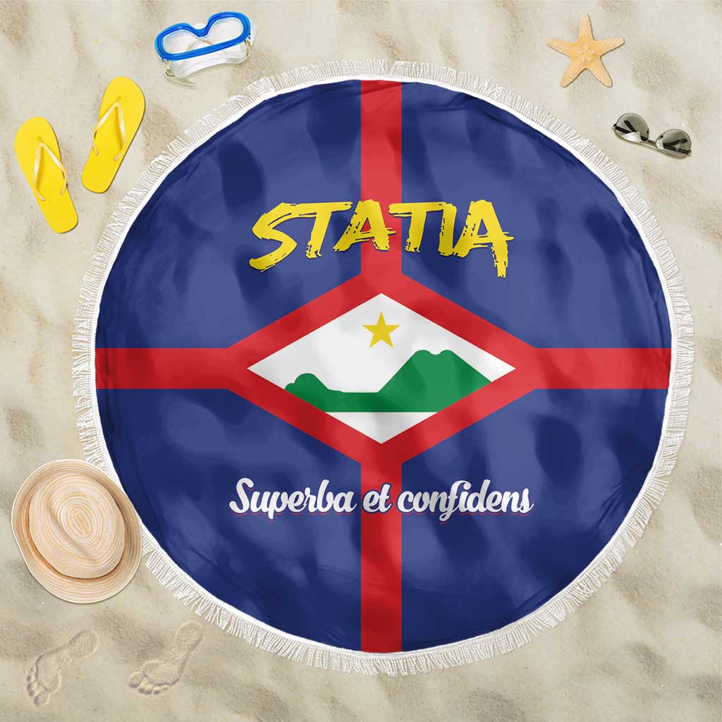 Round blue beach blanket with Statia crest design and “Superba et confidens” text, white fringe