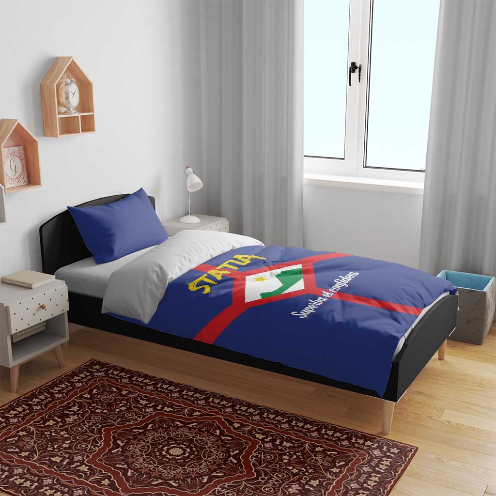 Blue bedding set on bed with STATIA crest, red cross stripe on duvet and pillowcases