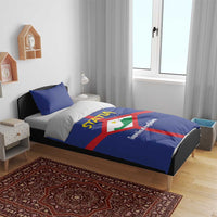 Blue bedding set on bed with STATIA crest, red cross stripe on duvet and pillowcases