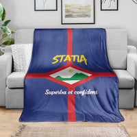 Blue coat of arms blanket draped on a sofa, showing "STATIA" and red cross