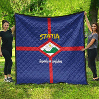 Blue quilt spread on lawn, red cross and Statia crest with yellow STATA and script text