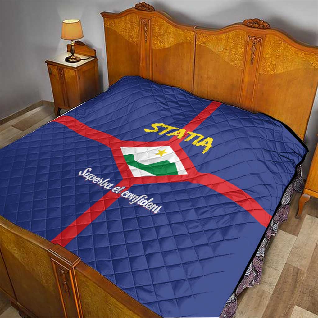 Blue quilt on bed with red cross and Statia crest, yellow STATA logo and quilted texture