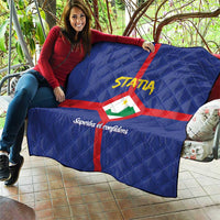Blue quilt held outdoors, red cross with Statia crest and yellow STATA text, quilted