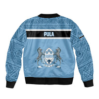Blue unisex bomber jacket back view with African pattern and centered crest graphic.