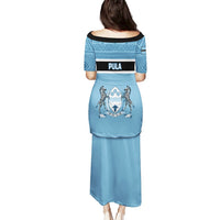 Blue long dress, back view, African geometric yoke and crest graphic across skirt