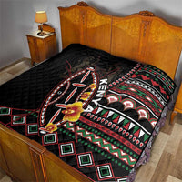 Black quilt on bed with tribal shield artwork, red-green stripes, and diamond border.